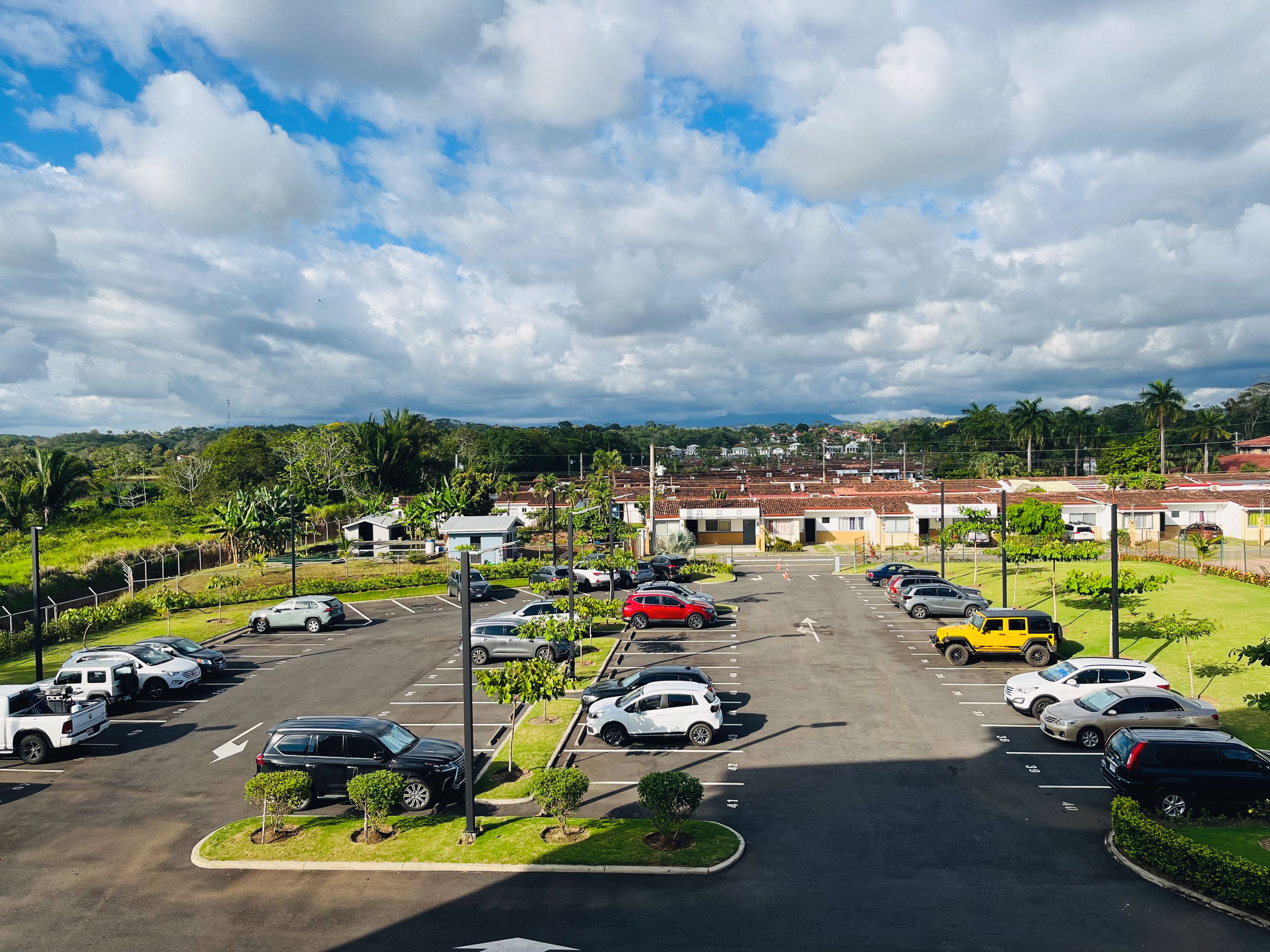 A parking lot with multiple cars and a few buildings in the background.
