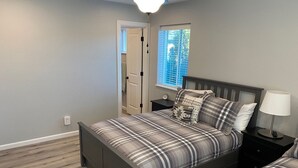 A bedroom with a bed, nightstands, a window, and a door.