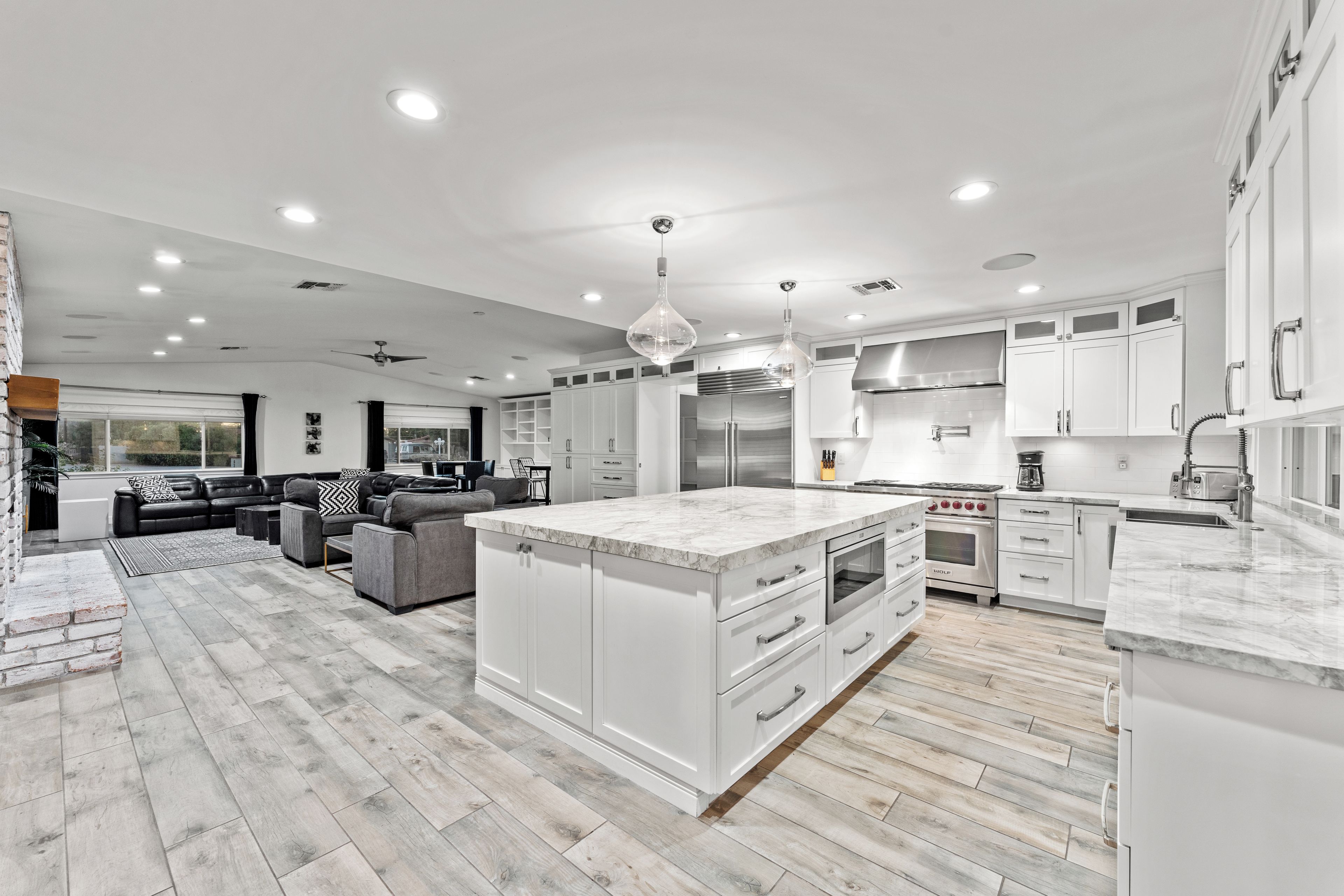 A spacious kitchen with white cabinetry, a large island, and modern appliances.