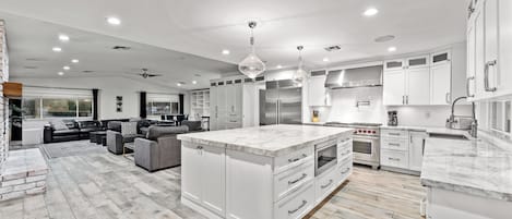 A spacious kitchen with white cabinetry, a large island, and modern appliances.