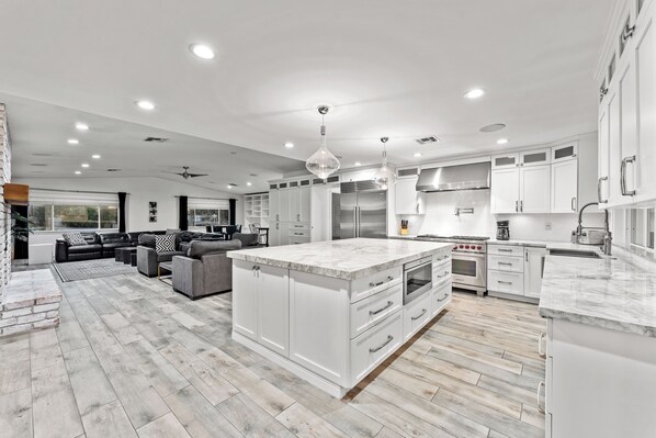 A spacious kitchen with white cabinetry, a large island, and modern appliances.