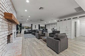 A spacious living area with a fireplace, seating, and a kitchen area with cabinets.