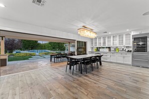 A modern kitchen with white cabinetry, a large island, and a dining area with black chairs.