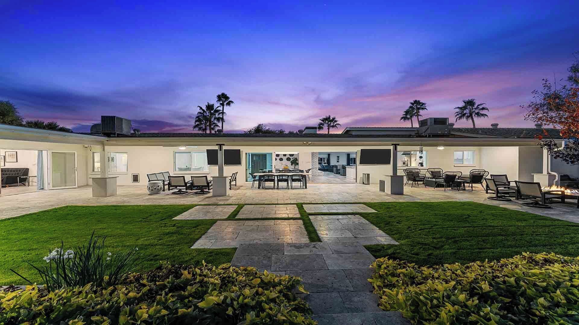Ein modernes Haus mit geräumiger Terrasse, Essbereich und gepflegtem Rasen.