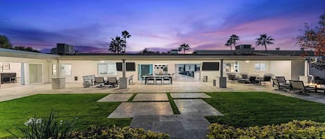 A modern house with a spacious patio, a dining area, and a well-maintained lawn.