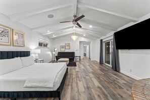 A spacious bedroom with a large bed, a ceiling fan, and a chandelier.