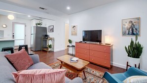 En moderne stue med sofa, sofabord og fjernsyn på et træskab.