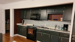Une cuisine moderne avec des meubles de couleur sombre, un four à micro-ondes, une cuisinière et un évier.