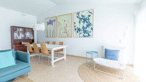 Een moderne woonkamer met een eethoek, een bank, een salontafel en een blauwe fauteuil.
