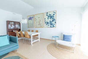 A modern living room with a dining area, a sofa, a coffee table, and a blue chair.