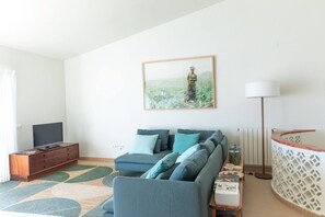 Un salon avec un canapé, un téléviseur, un tableau et une lampe.