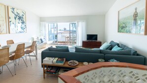 Een moderne woonkamer met een bank, een eettafel en stoelen. Er is een balkon met uitzicht op het landschap.