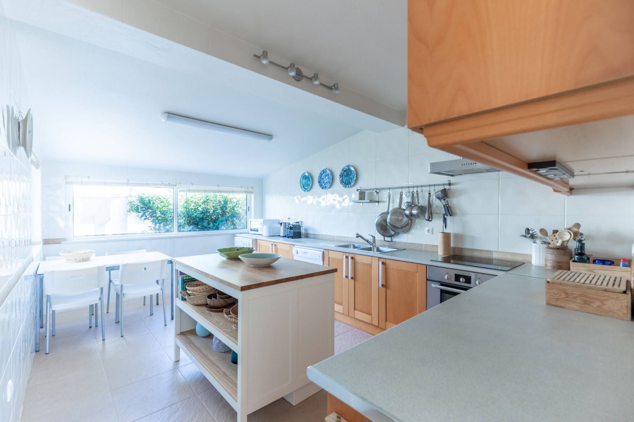 Une cuisine moderne avec des meubles blancs, un îlot central et un coin repas avec des chaises.