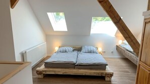 A bedroom with a sloped ceiling, a wooden bed frame, two bedside lamps, and a view through a skylight. - Langeoog by Interhome (Westerholt)