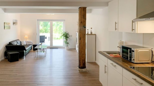 A modern apartment with a living room, kitchen, and a sliding glass door leading to a balcony. - Langeoog by Interhome (Westerholt)