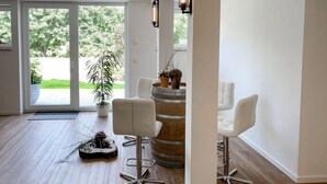 A modern interior with a wooden floor, white walls, and a large sliding glass door leading to a garden. There are two white chairs and a round wooden table with a metal base. - Langeoog by Interhome (Westerholt)
