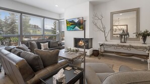 A modern living room with a fireplace, comfortable seating, and large windows. - Walk to the ski slopes, restaurants & shops.  Location is everything! (Steamboat Springs)