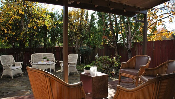 Un patio exterior cubierto con muebles de mimbre y una pequeña mesa con una planta.