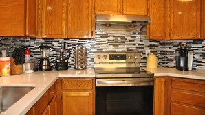 Una cocina con armarios de madera, estufa de acero inoxidable y salpicadero de azulejos.