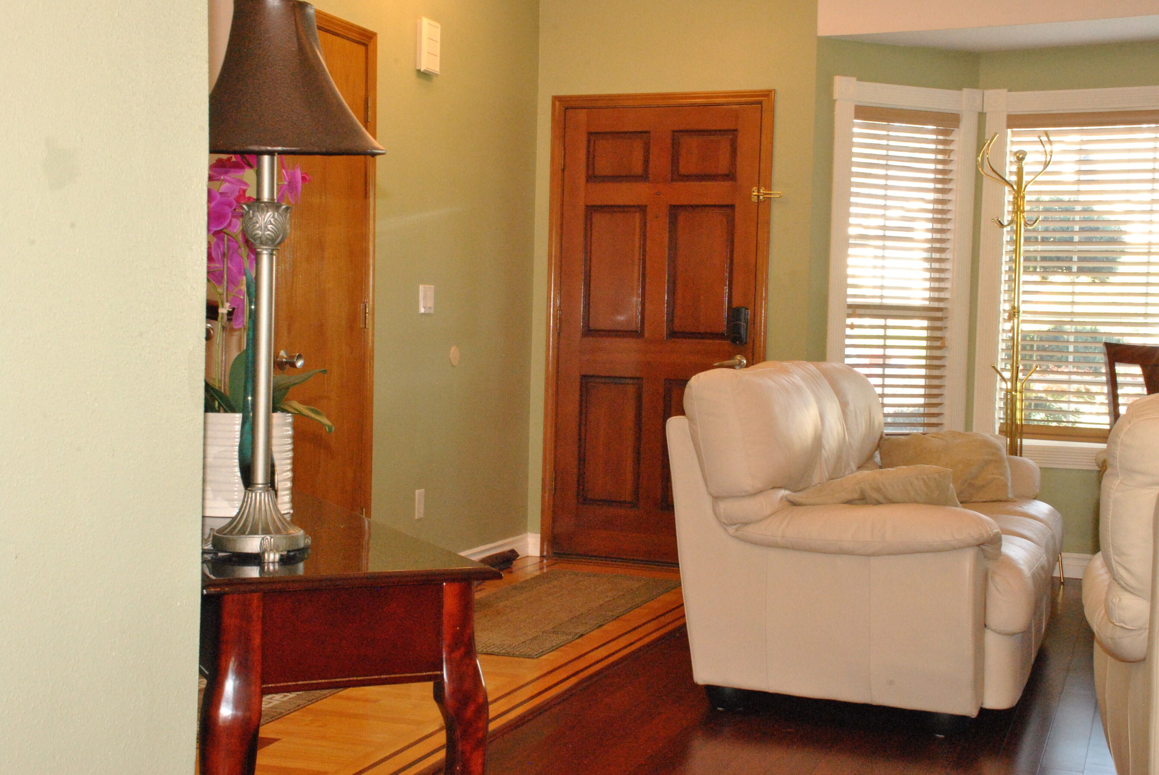 A living room with a wooden door, a white leather sofa, and a lamp.