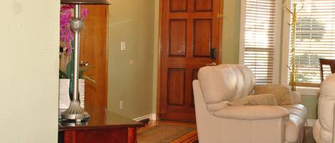 A living room with a wooden door, a white leather sofa, and a lamp.