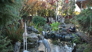 Un jardín con un estanque, rocas y dos estatuas.