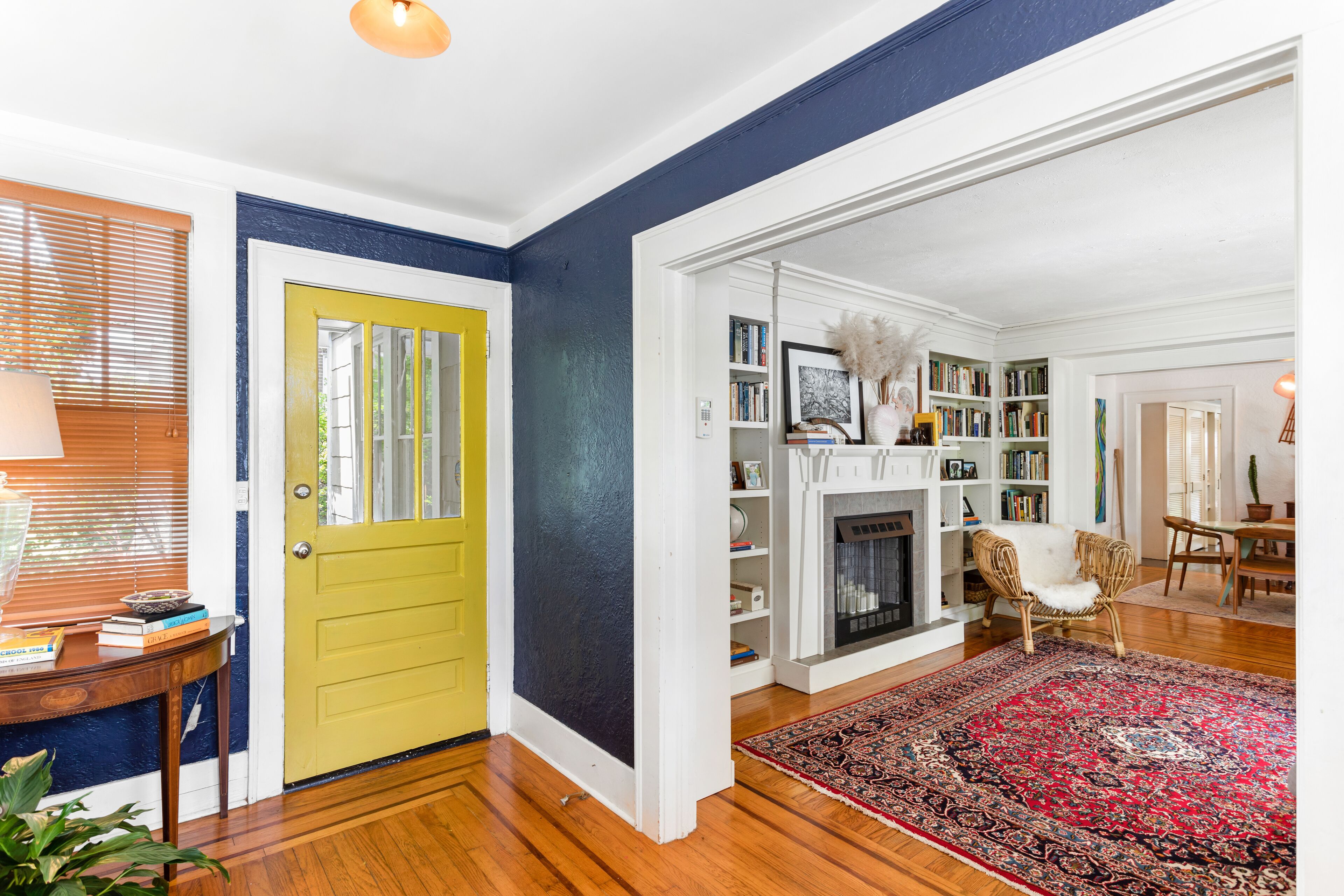 A living room with a yellow door, a fireplace, and a bookshelf.