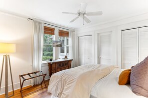 Cozy retreat with a large bed, ceiling fan, and dresser.