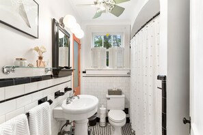 Features a sleek black and white tiled floor, white sink, and large mirror above the vanity.