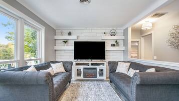 Smart-tv, een open haard, boeken en een kantoor