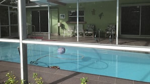 A covered swimming pool with a patio area, chairs, and a small table. - House with HEATED POOL and Outdoor Space (Sarasota)