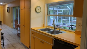 A kitchen with yellow cabinets, a double sink, and a window overlooking a backyard. - House with HEATED POOL and Outdoor Space (Sarasota)