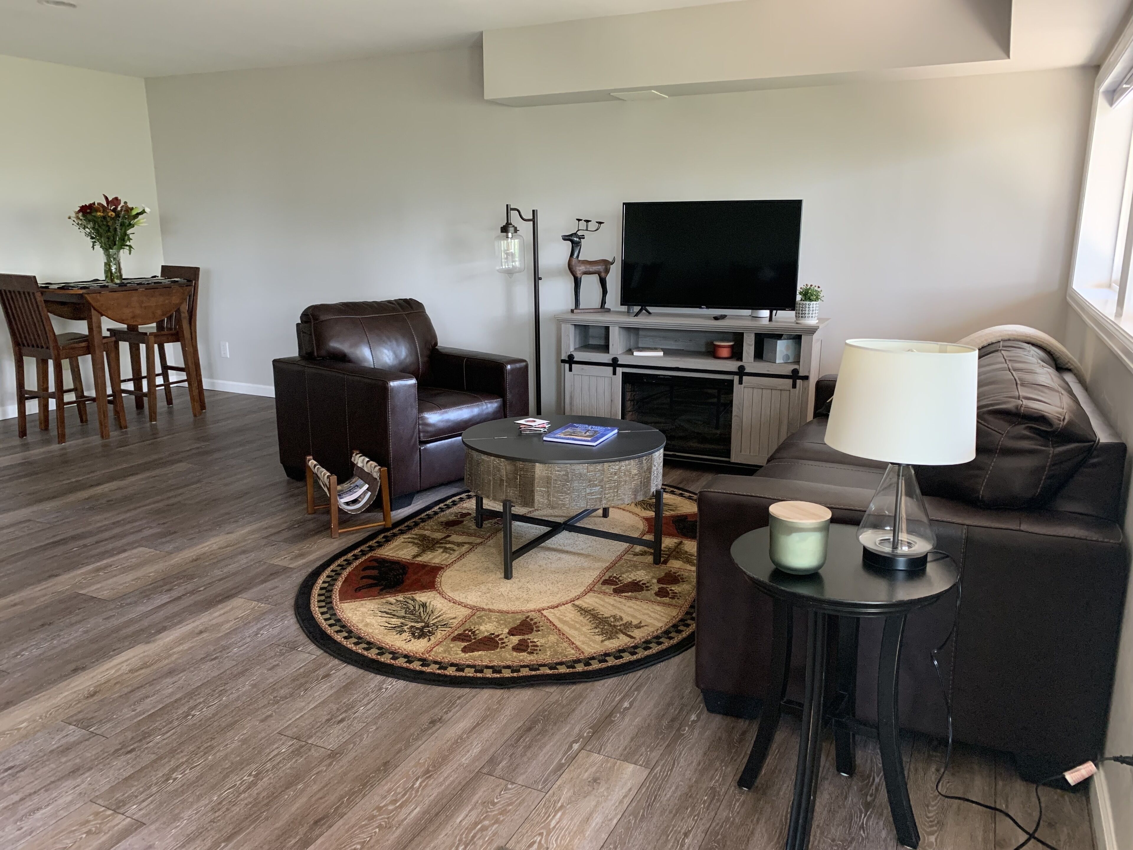 A modern living room with a leather sofa, a round coffee table, a TV, and a fireplace.