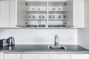 Uma cozinha com armários brancos, uma pia de aço inoxidável e uma torradeira sobre a bancada.