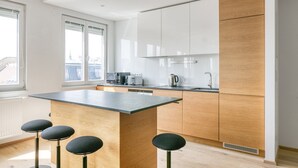 A modern kitchen with a central island, wooden cabinets, and bar stools.