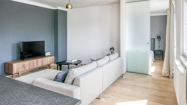 A modern living room with a sofa, TV, and a small table.