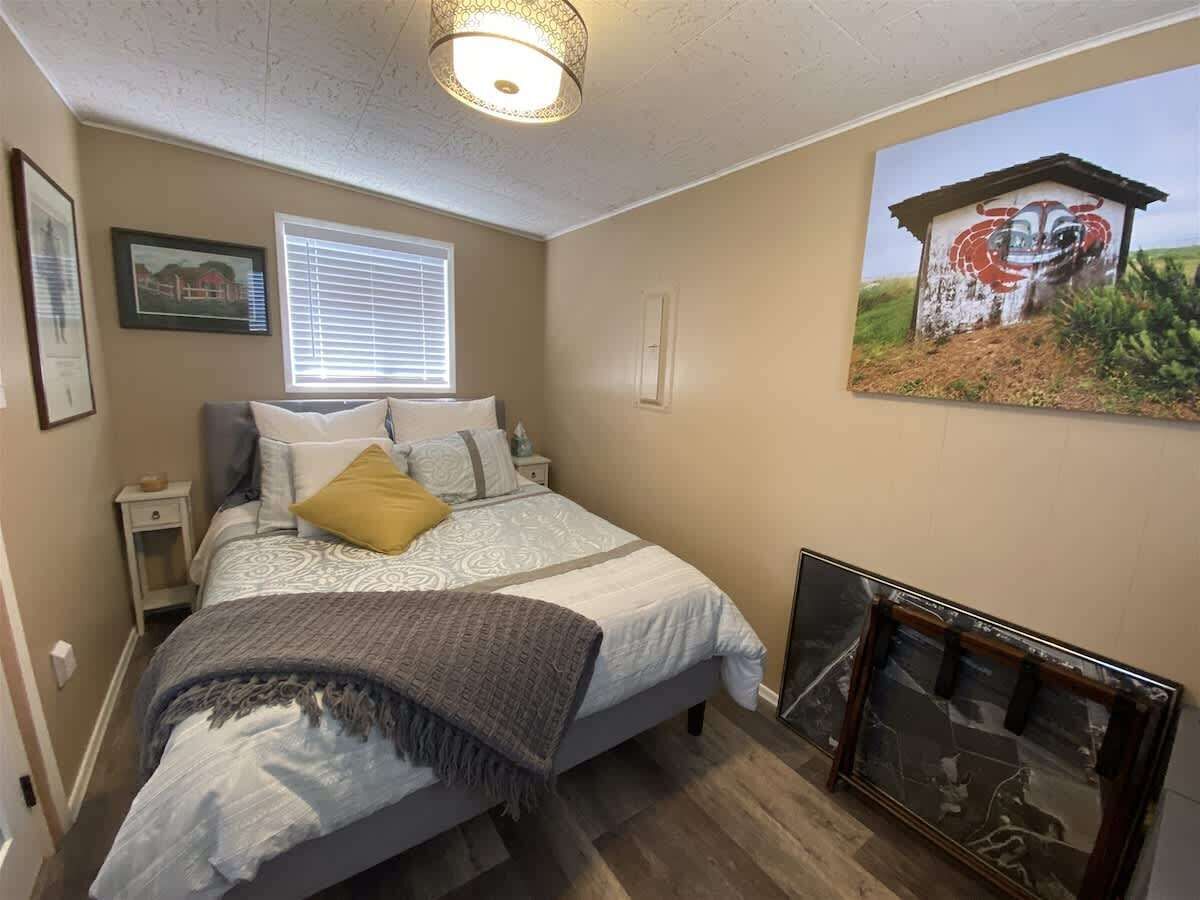 Una camera da letto con un letto, un comodino, una finestra con persiane, una lampada a parete e un quadro incorniciato.