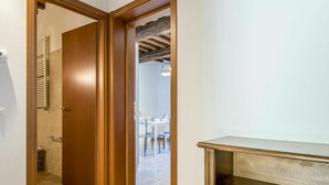 Un couloir avec une porte en bois donnant accès à une salle de bain et à un coin repas.