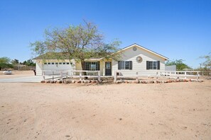 A single-story building with a white exterior, a front porch with white railings, and a tree in front. - Golden Desert Ranch - Hot Tub, Fire Pit and BBQ (Joshua Tree)