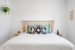 A bed with a bamboo headboard, two pillows, a hanging plant, and a macrame wall hanging. - Golden Desert Ranch - Hot Tub, Fire Pit and BBQ (Joshua Tree)