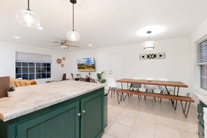 A kitchen with a central island, a dining table with chairs, and pendant lighting. - Golden Desert Ranch - Hot Tub, Fire Pit and BBQ (Joshua Tree)