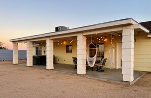 A covered outdoor area with a concrete floor, a hammock, and string lights. - Golden Desert Ranch - Hot Tub, Fire Pit and BBQ (Joshua Tree)