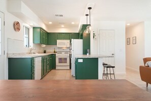 A modern kitchen with green cabinets, white appliances, and a wooden floor. - Golden Desert Ranch - Hot Tub, Fire Pit and BBQ (Joshua Tree)