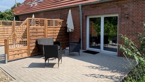 Un espace patio agrémenté d’un mur en briques, d’une porte en bois et d’une table avec des chaises.