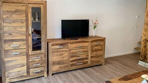 Une pièce avec un meuble en bois doté de nombreux tiroirs et sur lequel est posée une télévision.