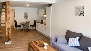 Un salon moderne avec une table basse en bois, un canapé gris et un escalier.