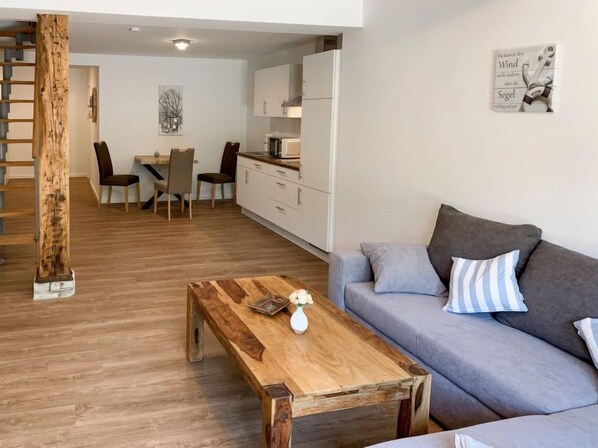 Un salon moderne avec une table basse en bois, un canapé gris et un escalier.