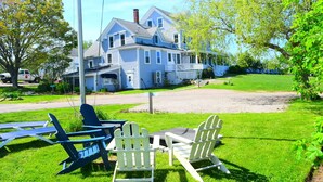 A large house with a porch, a lawn, and outdoor seating.