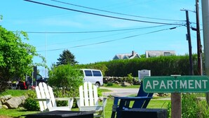 A grassy area with Adirondack chairs and a sign indicating an apartment complex.