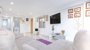A modern living room with a large grey sofa, a flat-screen TV, and a minimalist decor. - Apartment with Jacuzzi near the beach, Arenales (Los Arenales del Sol)